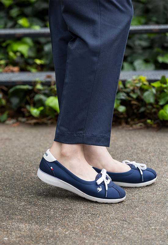 春のオフィスファッションに合う甲浅のネイビー軽量スニーカーとピンクシャツの着こなし