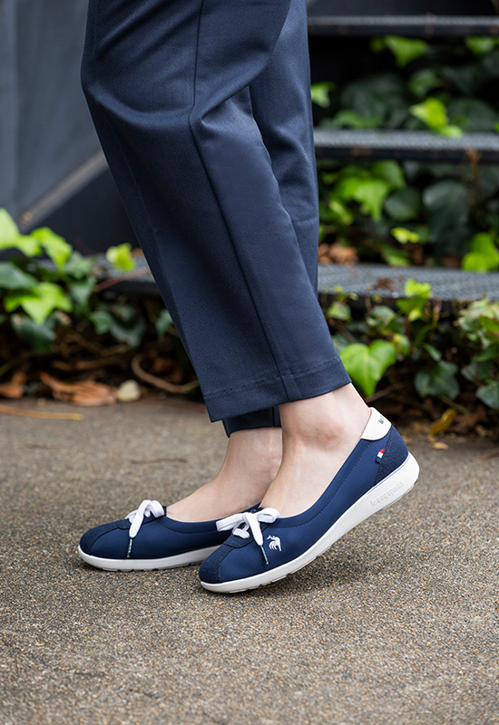 春のオフィスファッションに合う甲浅のネイビー軽量スニーカーとピンクシャツの着こなし