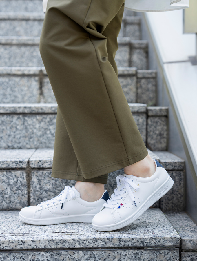 オフィスでのワイドパンツコーデに合うルコックスポルティフの白スニーカー「ラ ローラン」着用イメージ