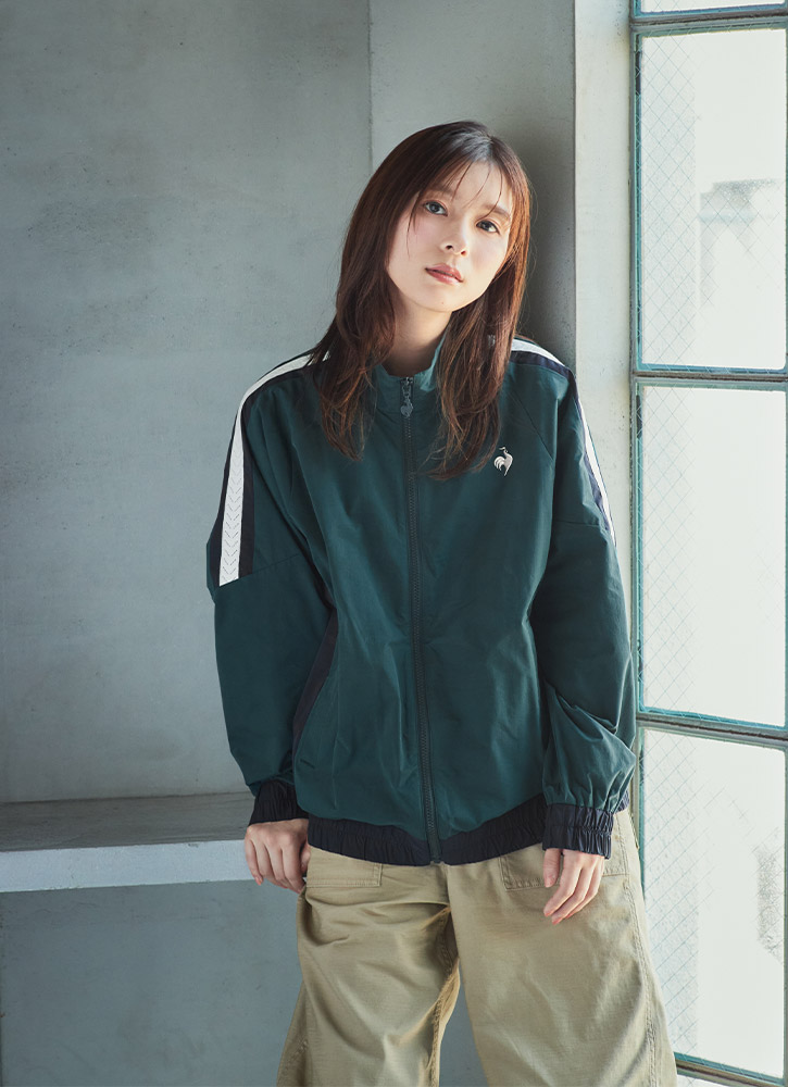 肩にラインが入ったグリーンのフルジップクロスジャケットを着てリラックスする芳根京子さん