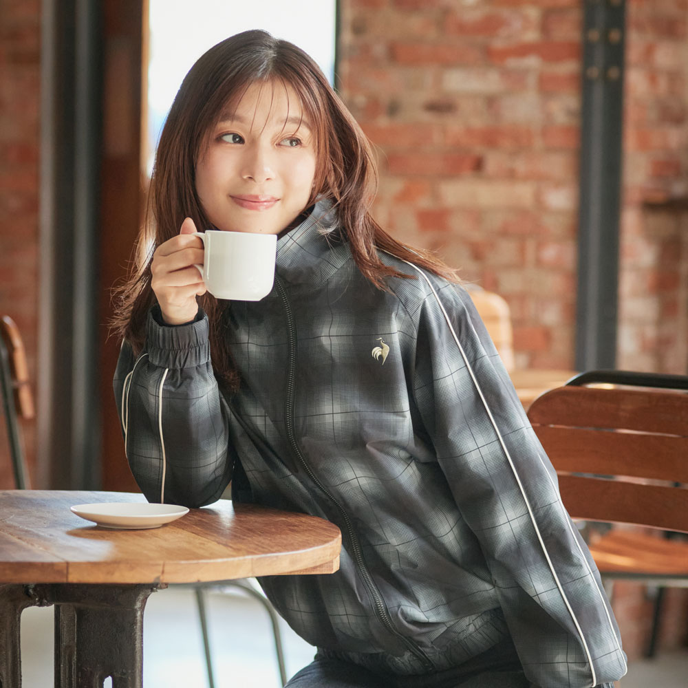 カフェでシックなチェック柄のグラフィックウィンドジャケットを着て寛ぐ芳根京子さん