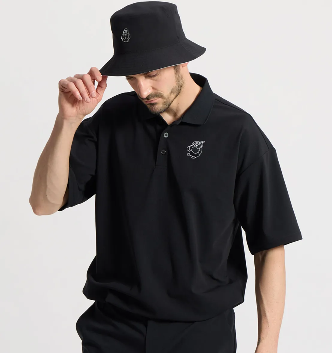 黒いペンギンのプリントが入ったポロシャツを着ている男性